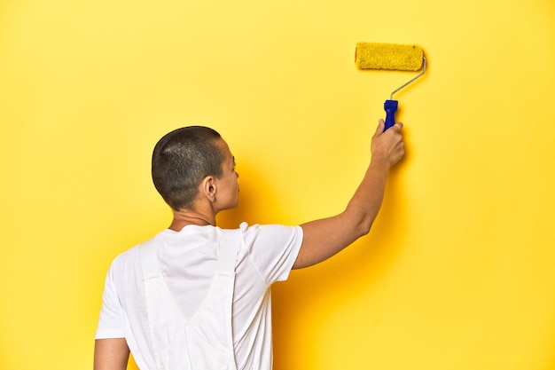 Young female painter with yellow paint roller studio backdrop