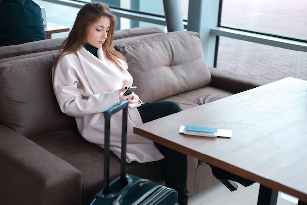 Giovane passeggero femminile utilizzando il telefono in aeroporto.