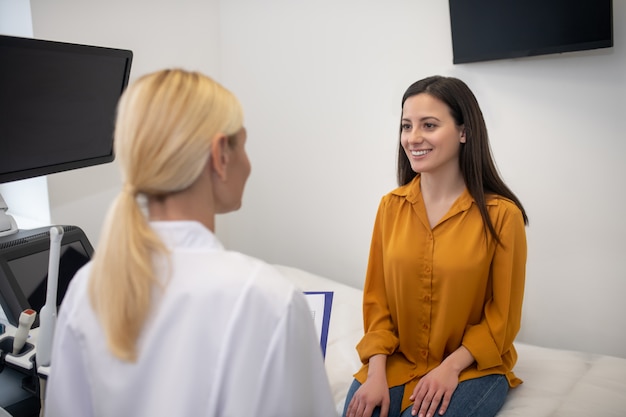 Foto giovane paziente di sesso femminile che si sente felice e sorridente mentre parla con il suo medico