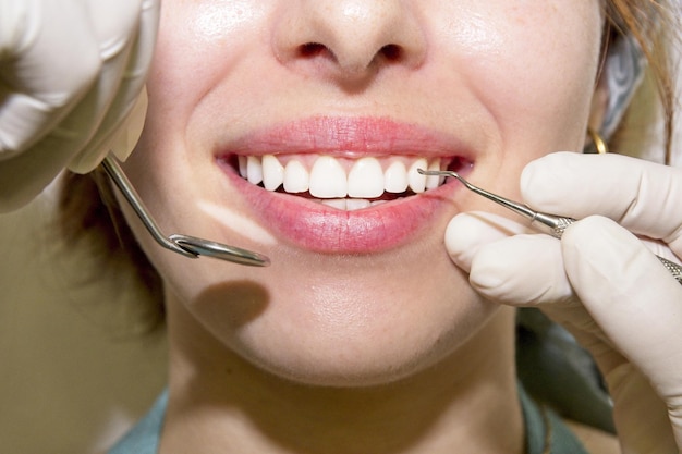 歯科診療所の医療コンセプトで歯医者が歯を検査している若い女性患者