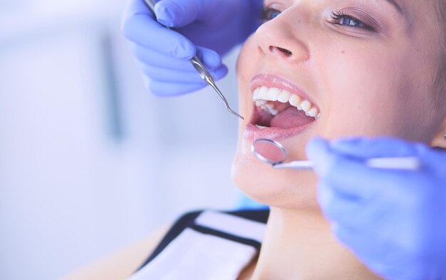 Young female patient with open mouth examining dental\
inspection at dentist office