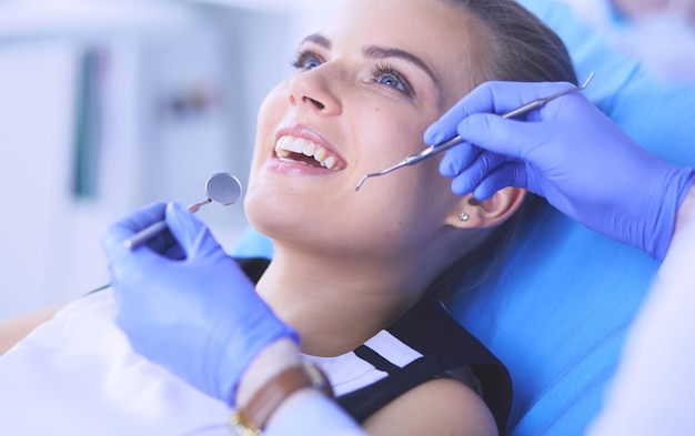 Young female patient with open mouth examining dental\
inspection at dentist office