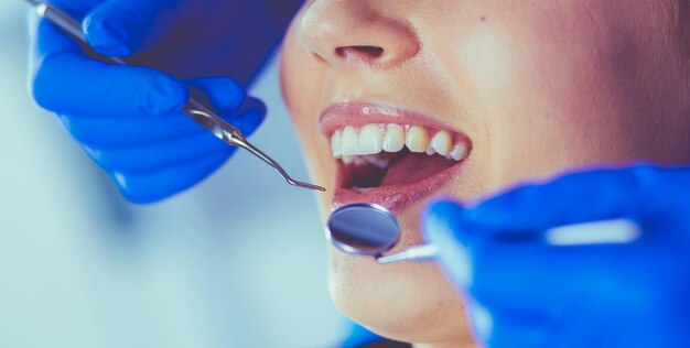 Young female patient with open mouth examining dental inspection at dentist office