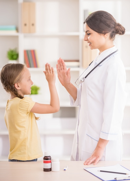 Young female pediatrician greeting her little cute patient.