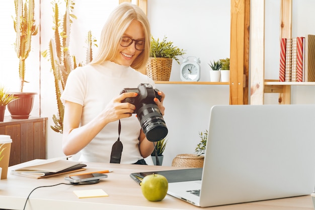 ホームオフィスで働く若い女性写真家アーティスト。