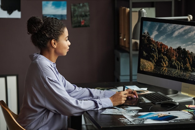 Photo young female photographer editing photos of nature on computer