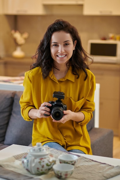 Young female photographer in a mustard shirt with camera in hands