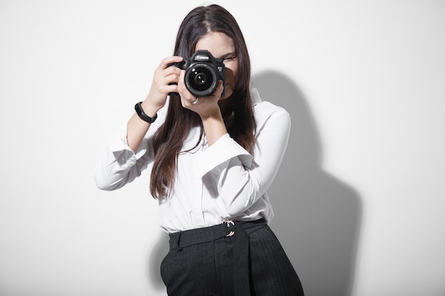 孤立した背景にSLRで写真を撮る若い女性