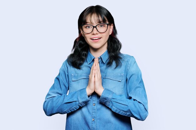 Young female pleading holding hands in prayer on white background