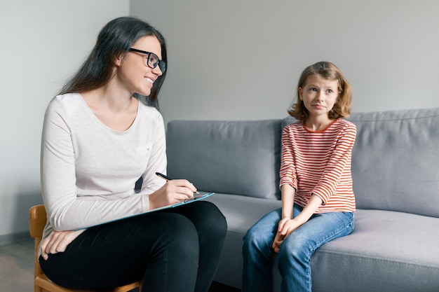 young female psychologist talking with patient child girl