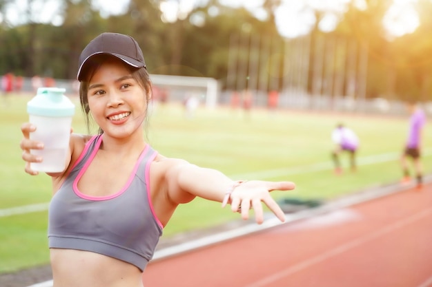 フィットネス トレーニングの後にリラックスし、一緒に運動するように誘うふりをする若い女性