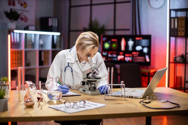 Молодая женщина-исследователь смотрит в микроскоп в науке о жизни