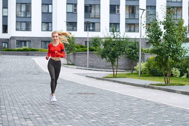 フーディの若い女性ランナーが街でジョギングします。