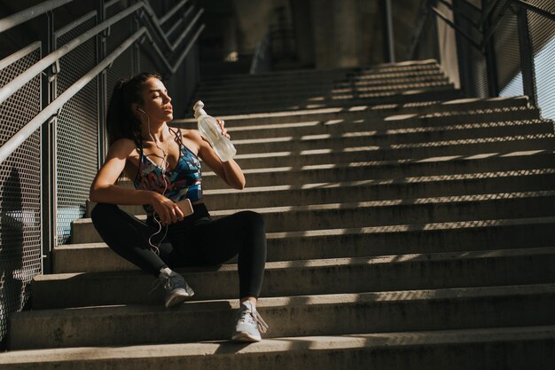 Young female runner resting on stairs