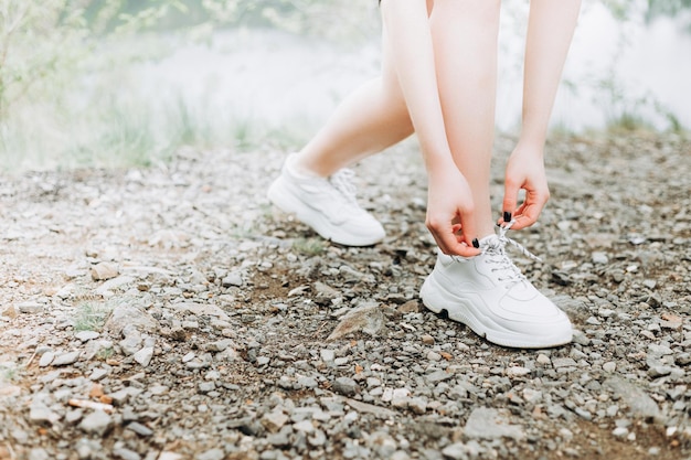 湖の近くの朝の森のトレイルで実行する前に腕と脚を伸ばす若い女性ランナー