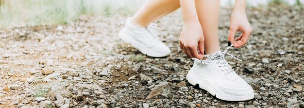 湖の近くの朝の森のトレイルで実行する前に腕と脚を伸ばす若い女性ランナー