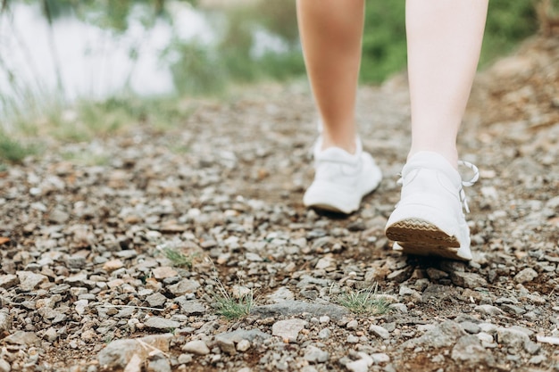 Young female runner stretching arms and legs before running at\
morning forest trail near lake