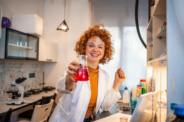 Foto giovane scienziata che fa esperimenti in laboratorio. donna positiva felice che fa una ricerca microbiologica