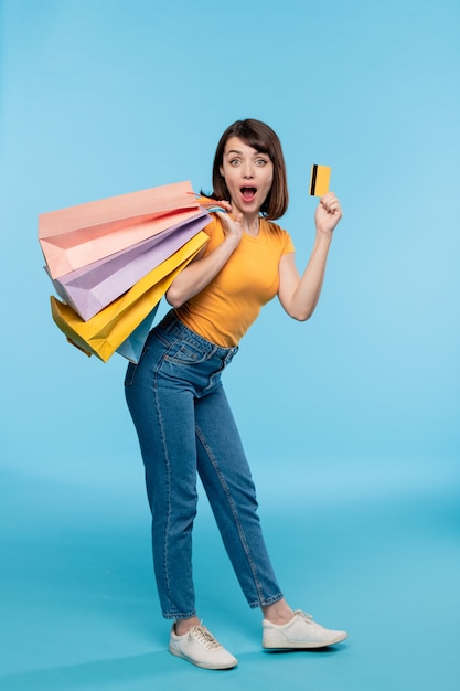 Young female shopaholic in casualwear boasting with credit card while standing