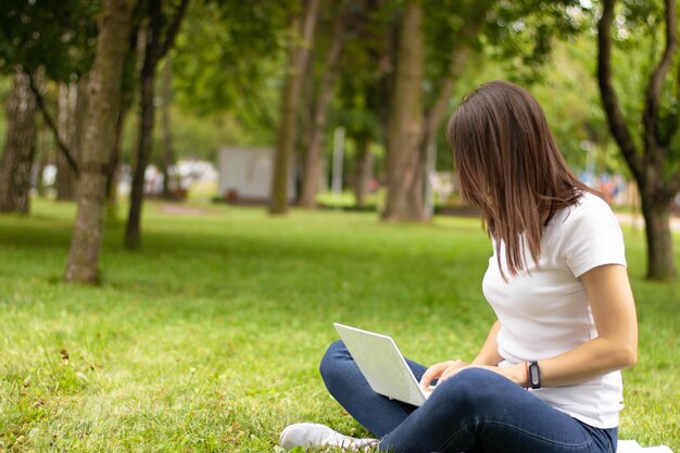 Photo young female side view. woman working on laptop computer with blank black blank screen