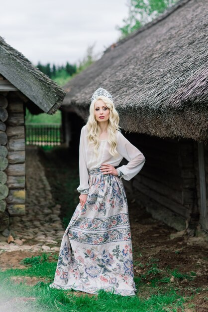 A young female of Slavic appearance with crown, kokoshnik on the MidSummer, village, homestead