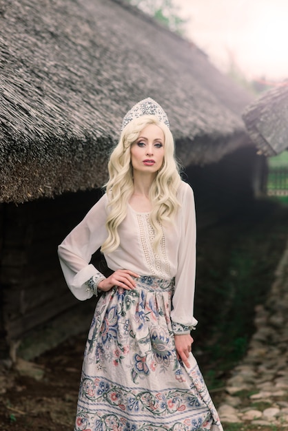 A young female of Slavic appearance with crown, kokoshnik on the MidSummer, village, homestead