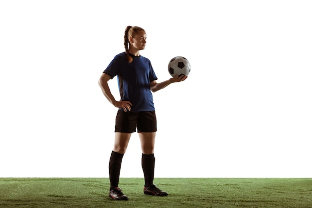 Young female soccer or football player with long hair posing confident holding ball