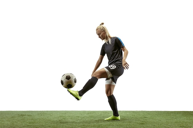 긴 머리에 운동복을 입고 부츠를 신은 젊은 여성 축구 선수나 축구 선수는 흰색 배경에서 점프 목표를 위해 공을 차고 있습니다. 건강한 생활 방식, 프로 스포츠, 운동, 운동의 개념.