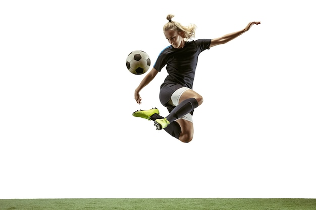 Young female soccer or football player with long hair in sportwear and boots kicking ball