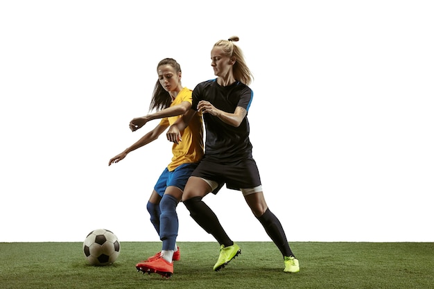 Young female soccer or football players with long hair in sportwear and boots training on white background. Concept of healthy lifestyle, professional sport, motion, movement. Fight for goal.