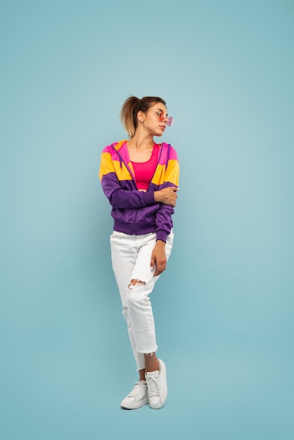 Young female standing in blue studio and looking away