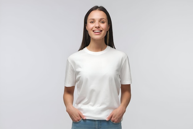 Young female standing in front of camera in white Tshirt and blue jeans isolated on background