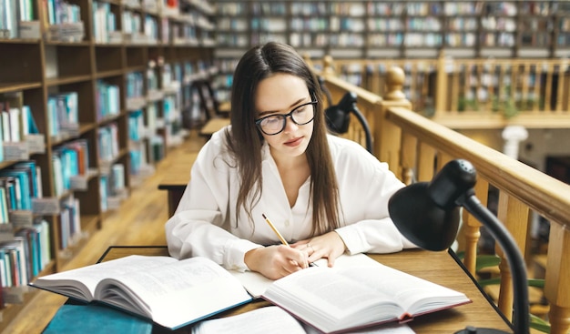 Young female student doing assignments in library