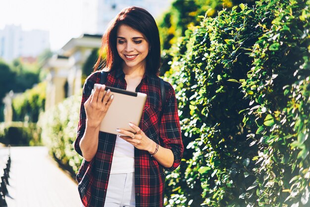 Young female student enjoying watching video on webpage using digital tablet and internet connection