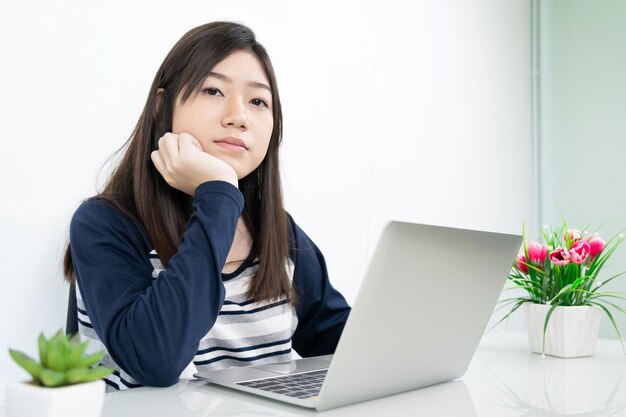 Young female student sitting in living room using laptop at desk learning online