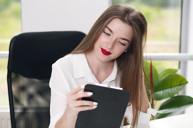 Young female student sitting in the office solving problems.