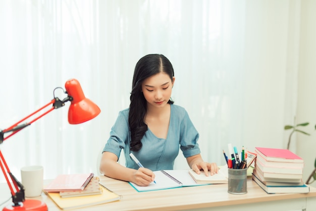 a young female student sitting at the table, using tablet when studying.