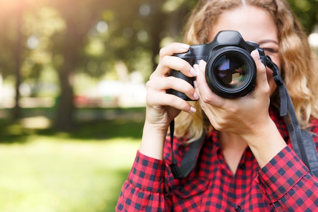 Young female student taking photos in the park with camera. Photography classes, education and remote working concept, copy space, closeup