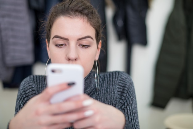 young female student using a mobile phone during the break in the classroom