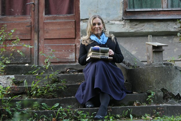 A young female student with blond hair and a bag of books in her hands