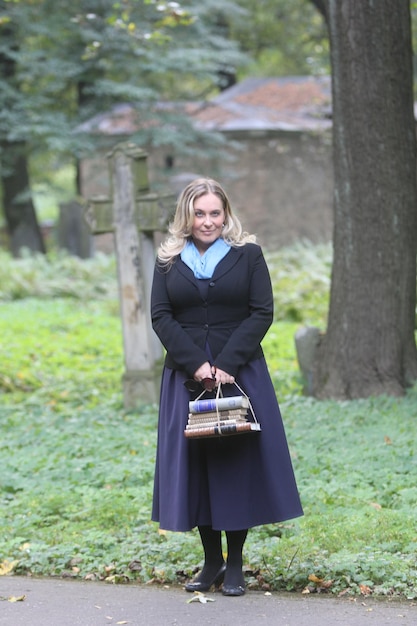 A young female student with blond hair and a bag of books in her hands