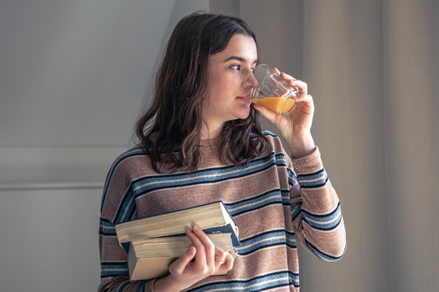 A young female student with books in her hands in the room