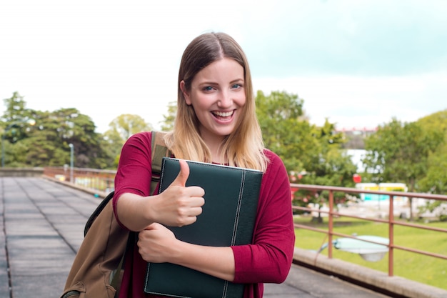 Young female student with folders in college campus 