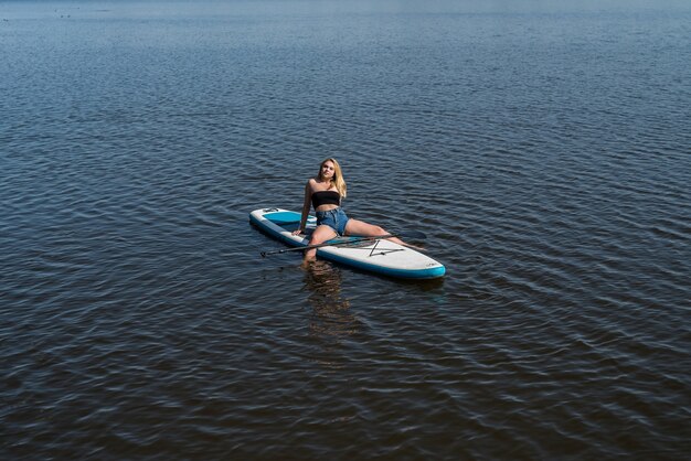 Фото Молодая женщина-серфер, лежа на доске, отдыхает на природе, свобода в летнее время