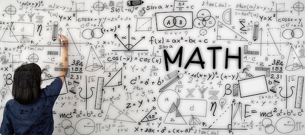 Young female teacher is writing math formulas and equations on\
whiteboard to explain educational material task to her pupils or\
students