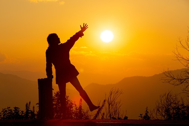 Young female tourist carrying luggage at sunset