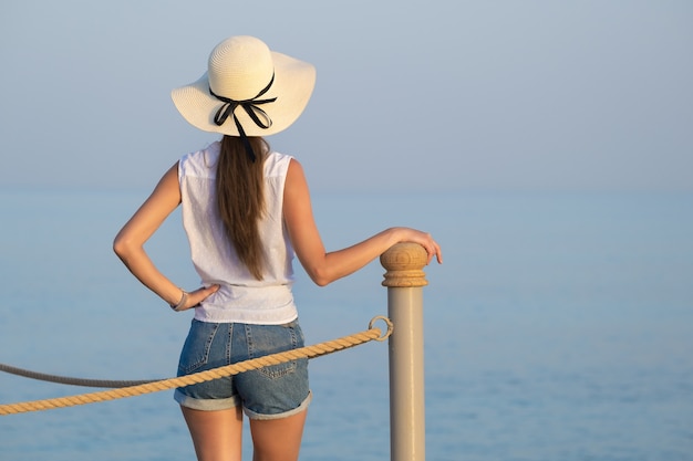 young female tourist in casual clothes enjoying warm sunny day on sea shore.