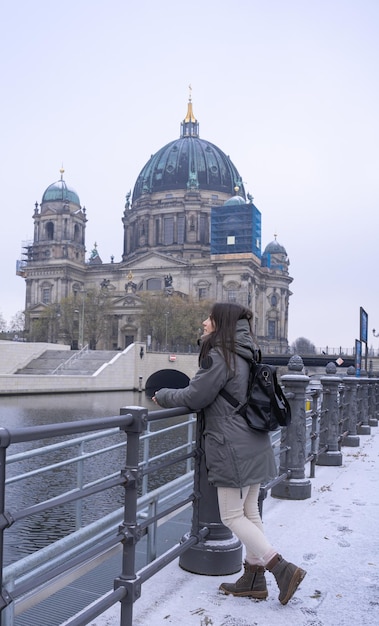 Young female tourist leaning against the river and cathedral in Berlin Germany