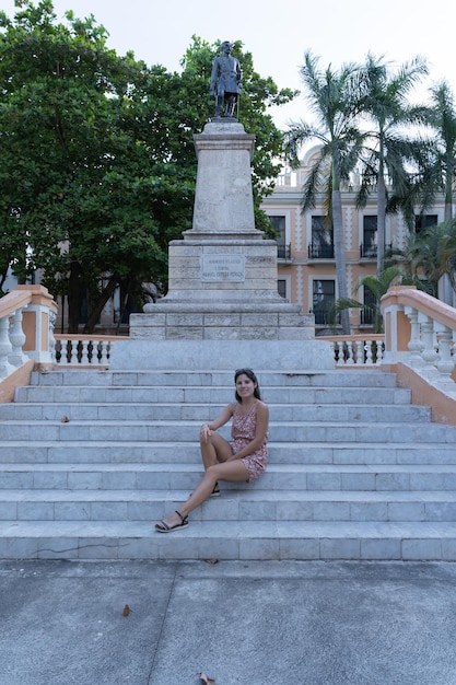 Photo young female tourist sitting on the stairs next to the manuel cepeda monument