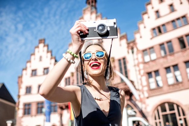 Young female tourist with photo camera enjoying visiting the old city center of Frankfurt city